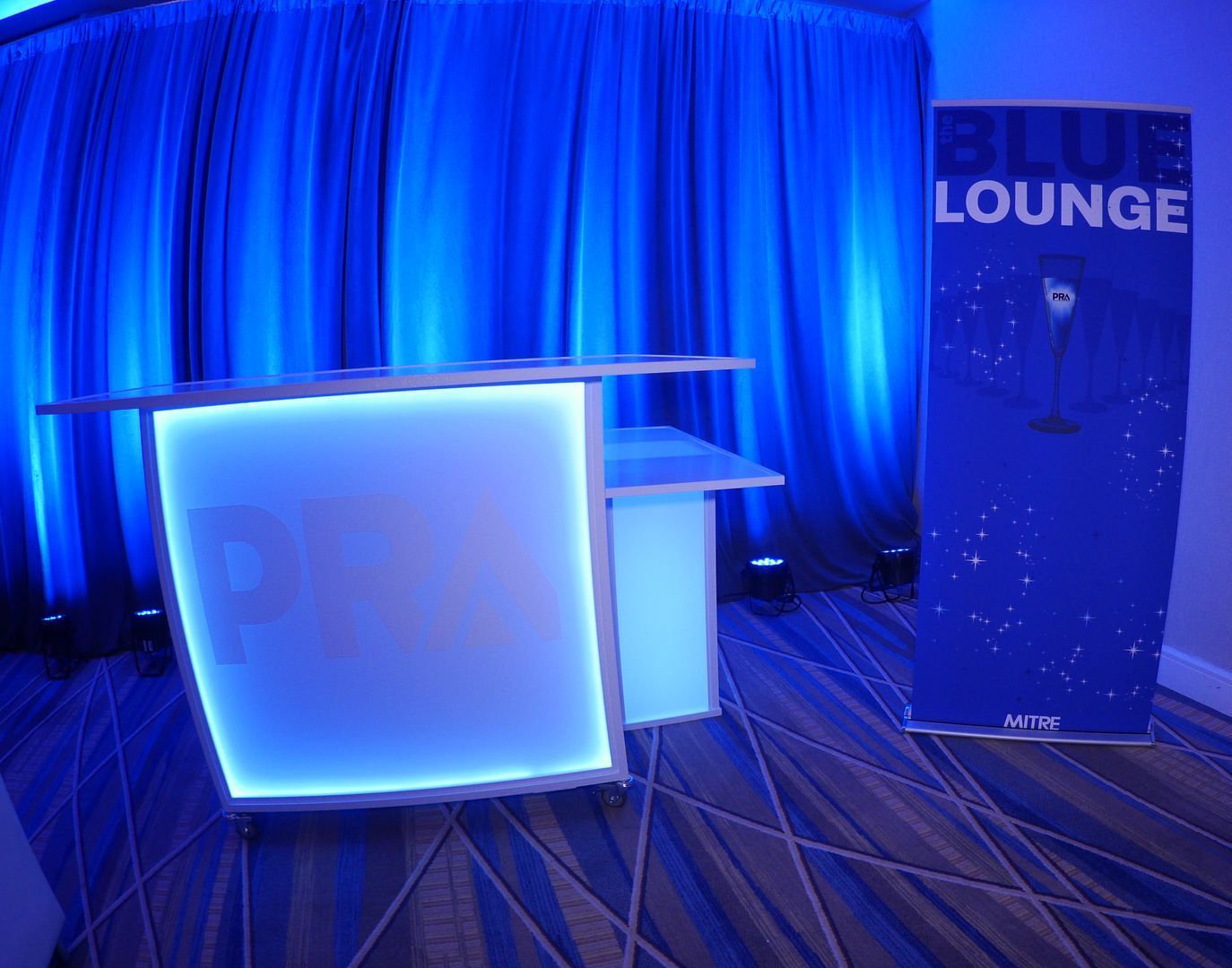 A blue lounge sign is next to a bar in a room.
