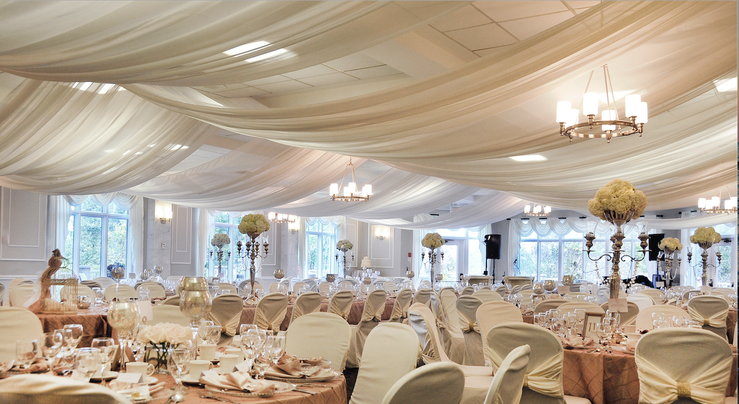 A large room with tables and chairs set up for a wedding reception.