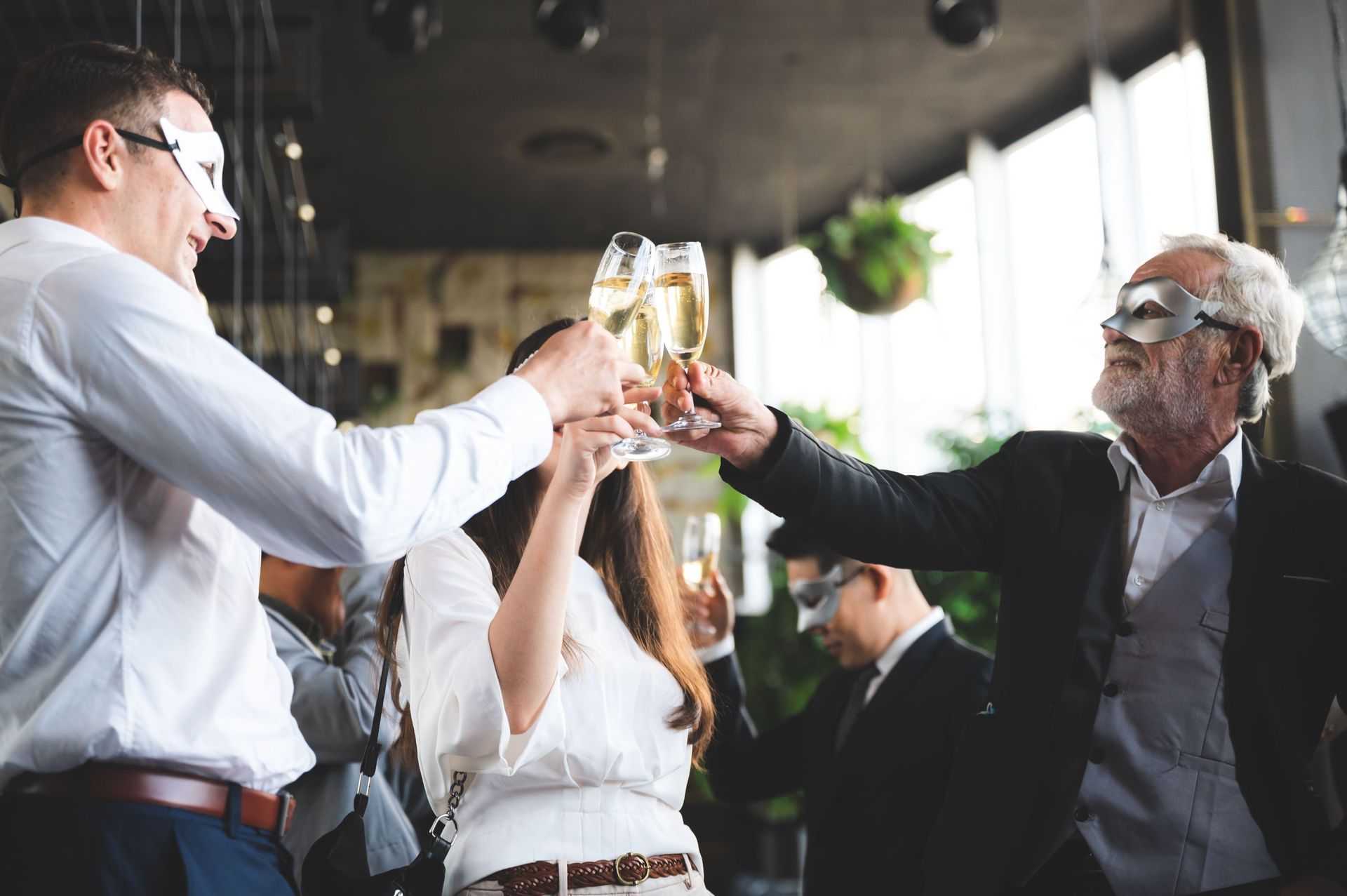 A group of people wearing masks are toasting with champagne glasses.