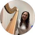 A woman is standing next to a harp and smiling.