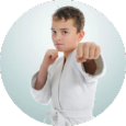 A young boy in a white karate uniform is standing in a circle.