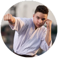 A young man in a white karate uniform is standing in a circle.