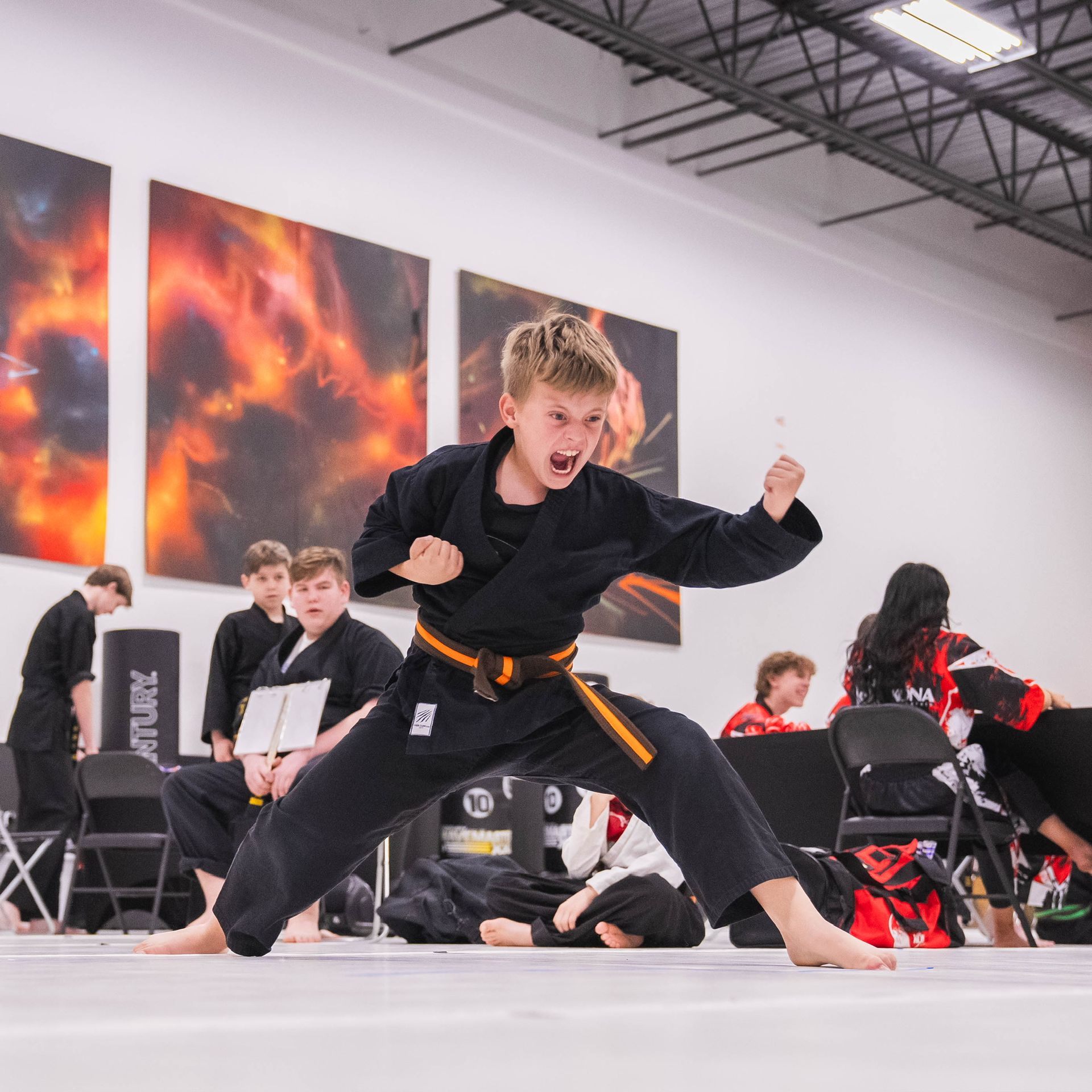 A young boy is practicing martial arts in a gym.