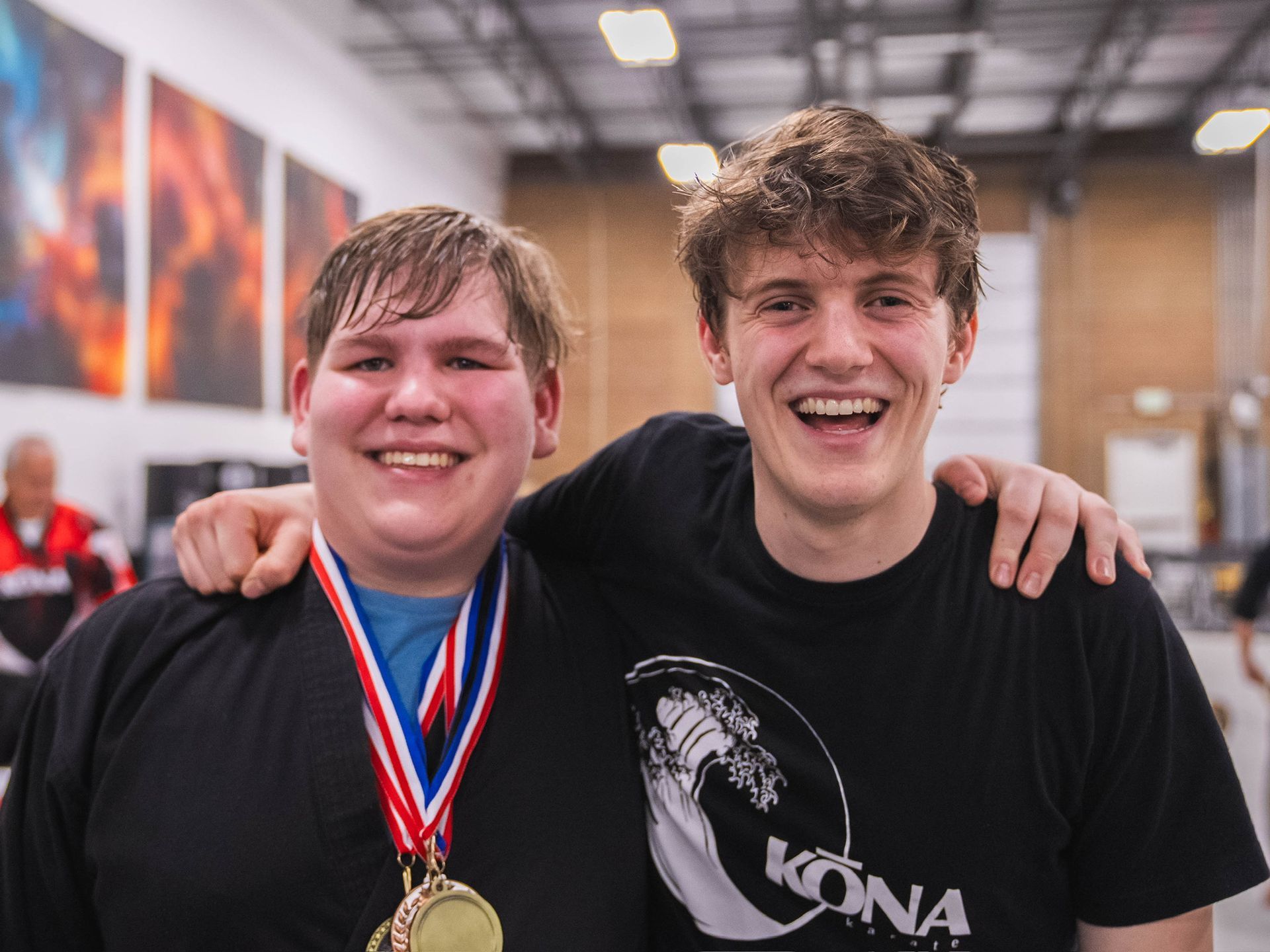 Two young men are posing for a picture and one of them is wearing a medal.