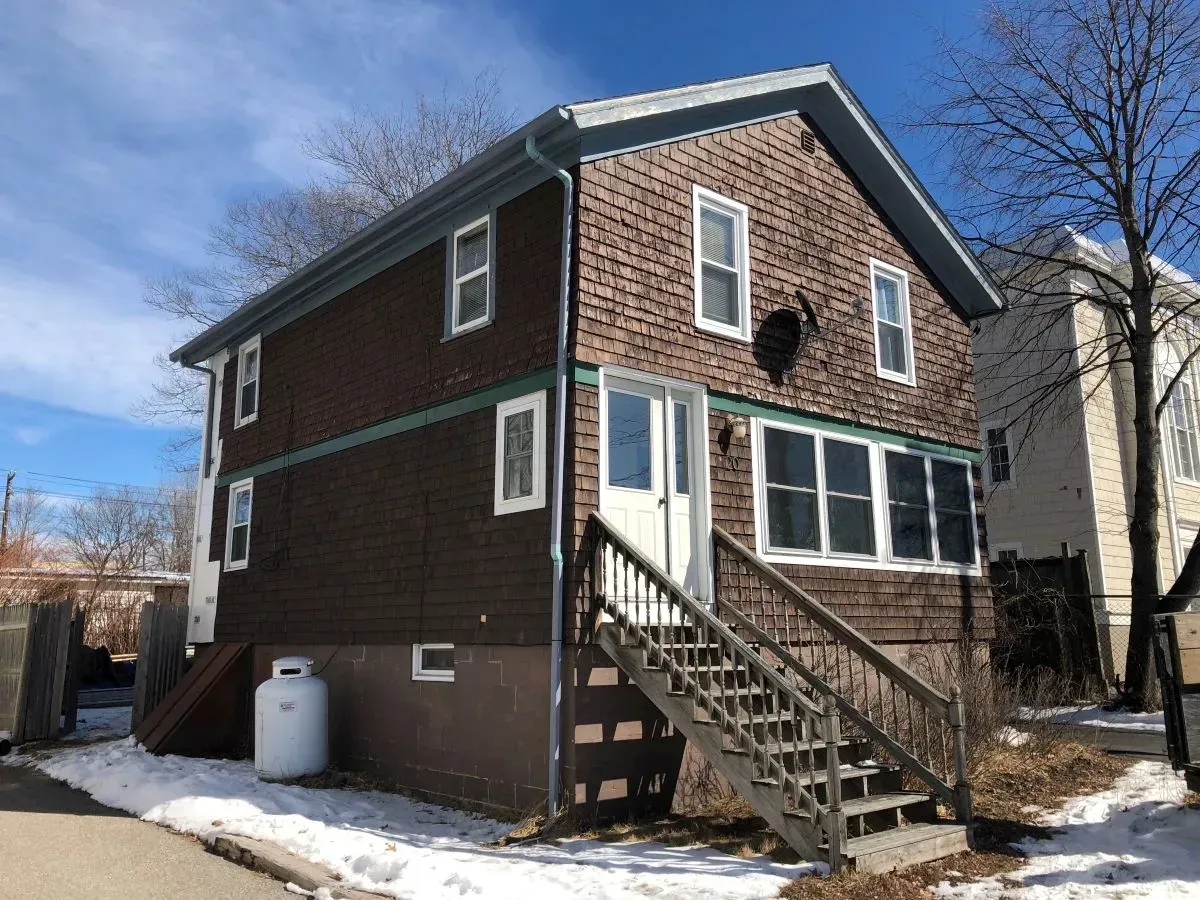 A brick house with stairs and a propane tank in front of it