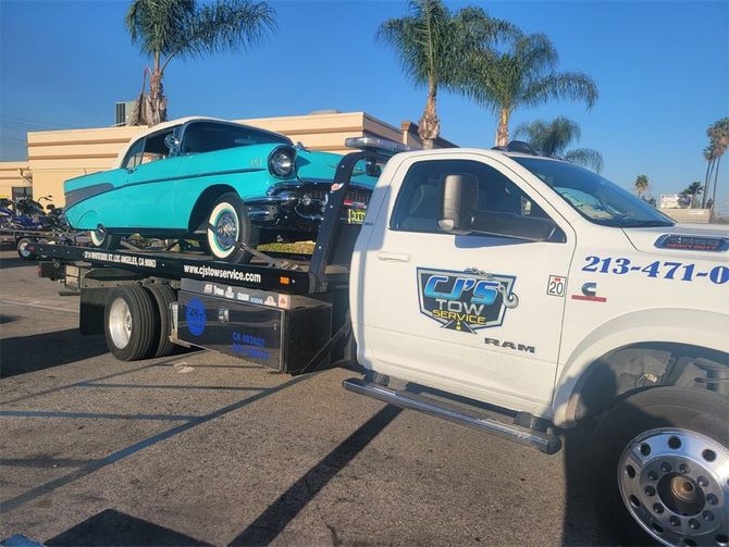 Cj’s Tow Service Truck is carrying a blue car