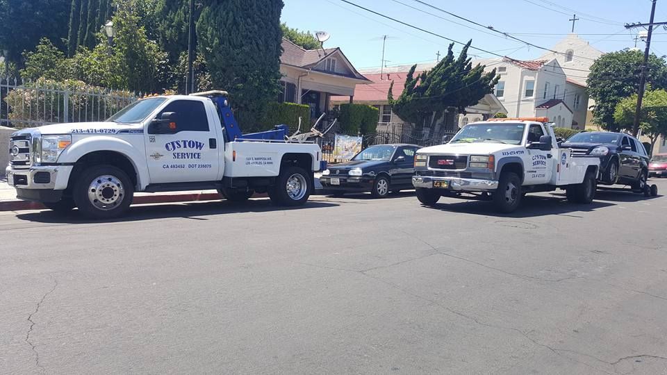 Three tow trucks are parked on the side of the road.