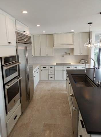 Modern kitchen with white cabinets, stainless steel appliances, and dark island countertop.