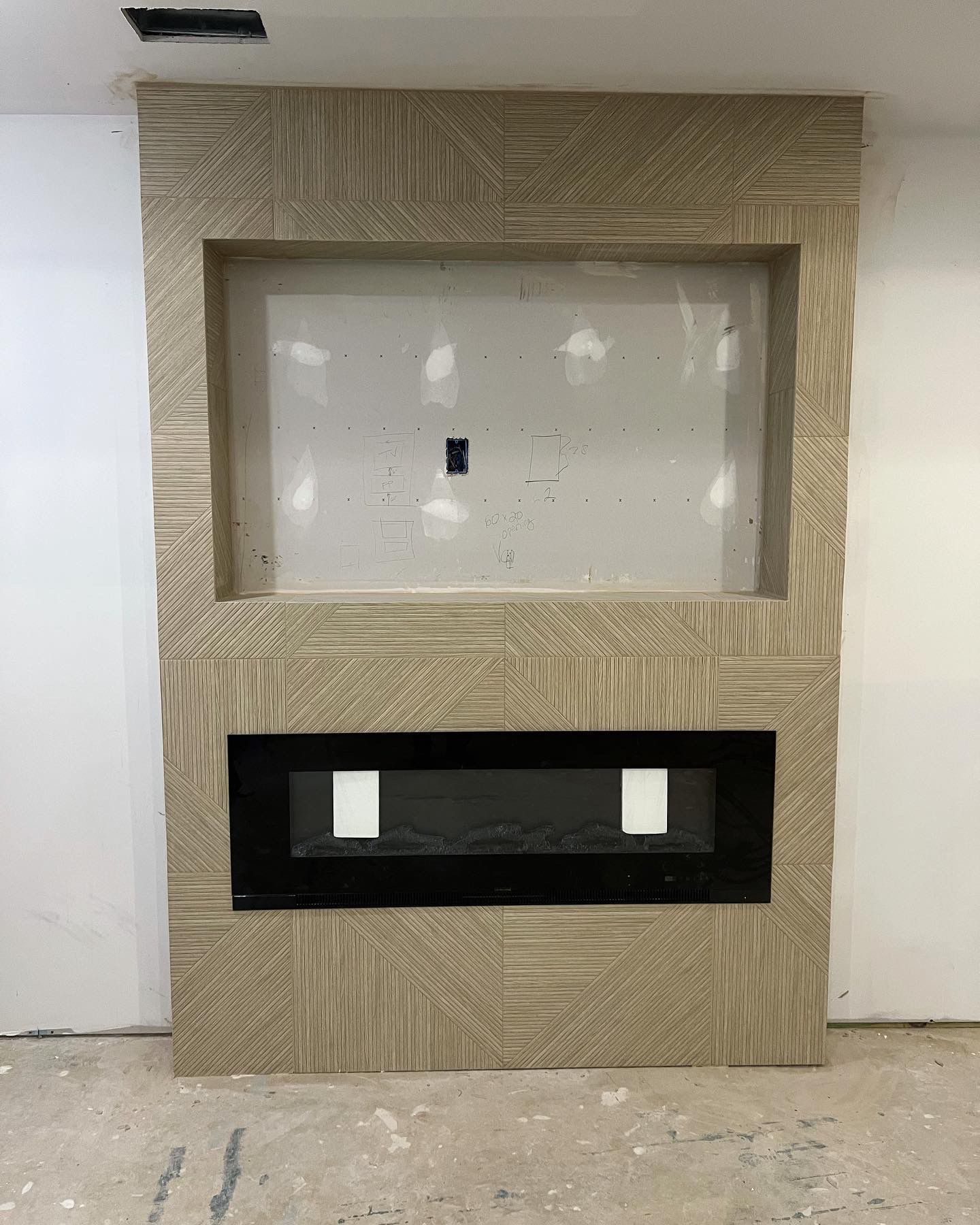 Fireplace surround with textured beige design, black fireplace and space for TV.