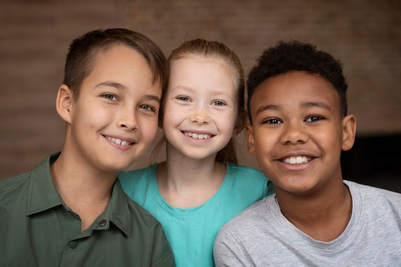 Three children , a boy and two girls , are posing for a picture together.