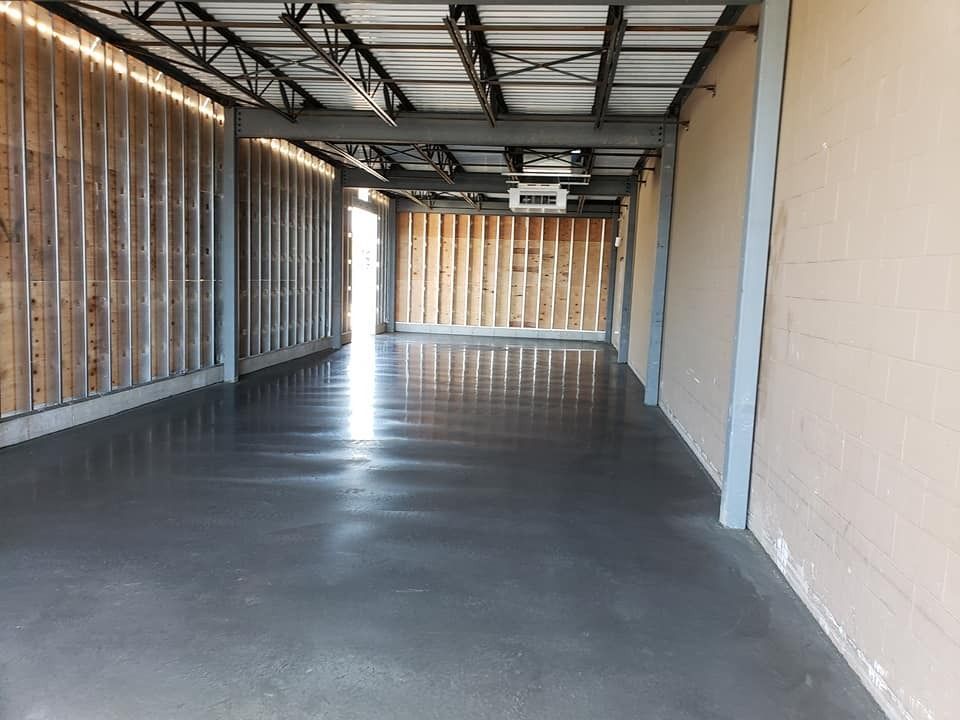 A large empty room with a concrete floor and wooden walls