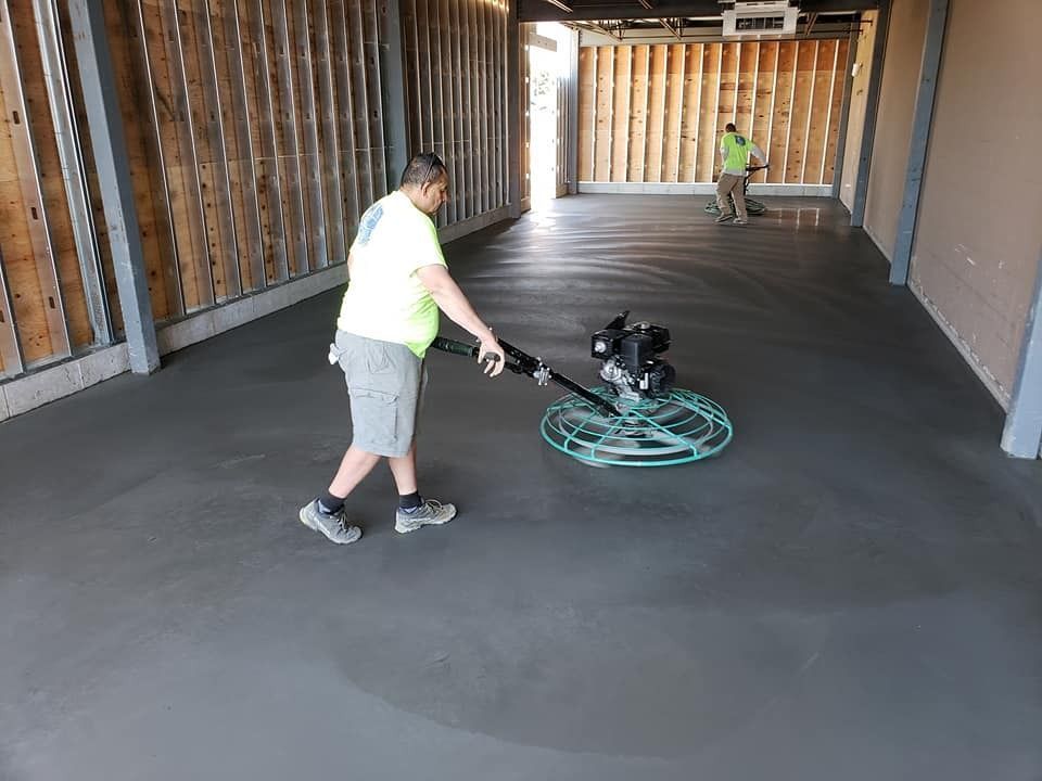 A man is using a machine to finish a concrete floor.