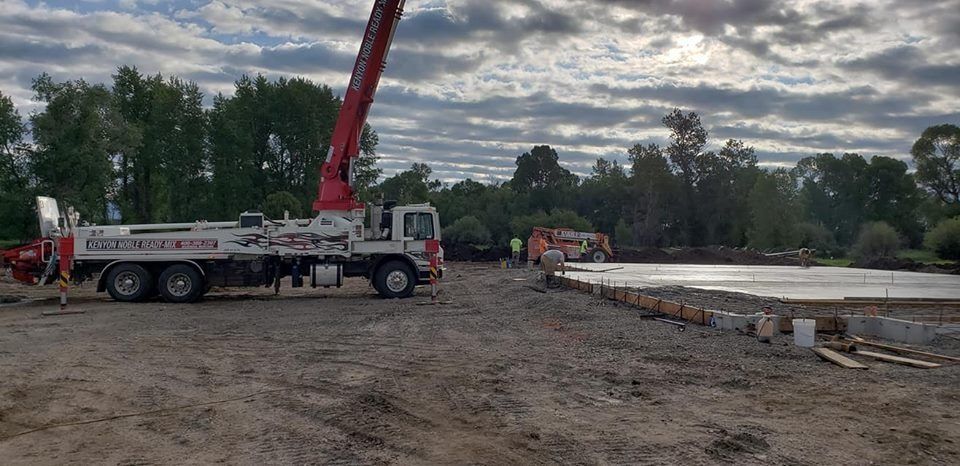 A concrete pump truck is sitting on top of a dirt field.