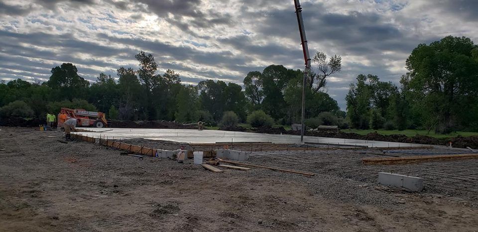 A construction site with a crane pouring concrete into the ground.