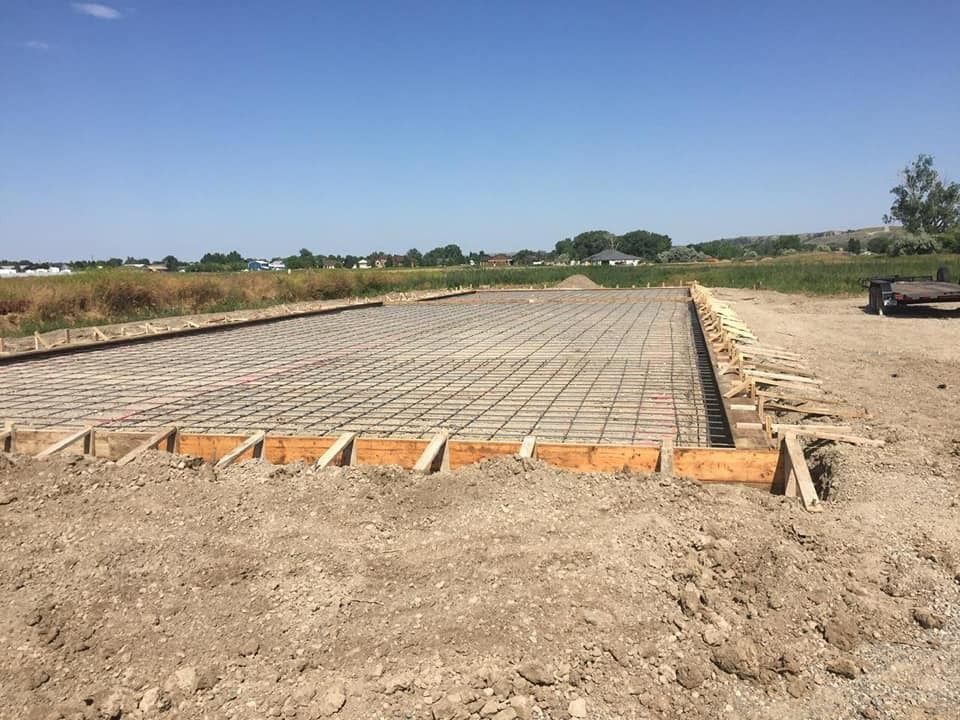 A concrete foundation is being built in a dirt field.