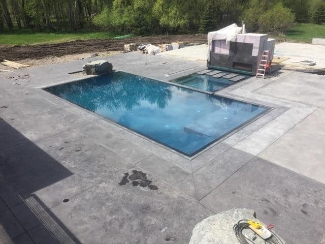 A large swimming pool is being built in a backyard.