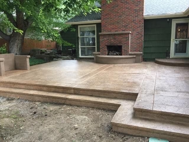 A patio with stairs and a fireplace in the backyard of a house.
