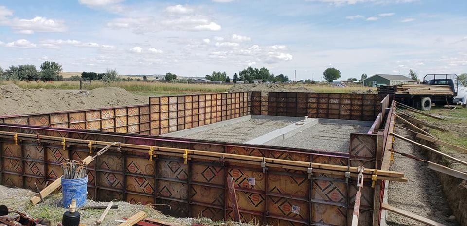 A large swimming pool is being built in a dirt field.