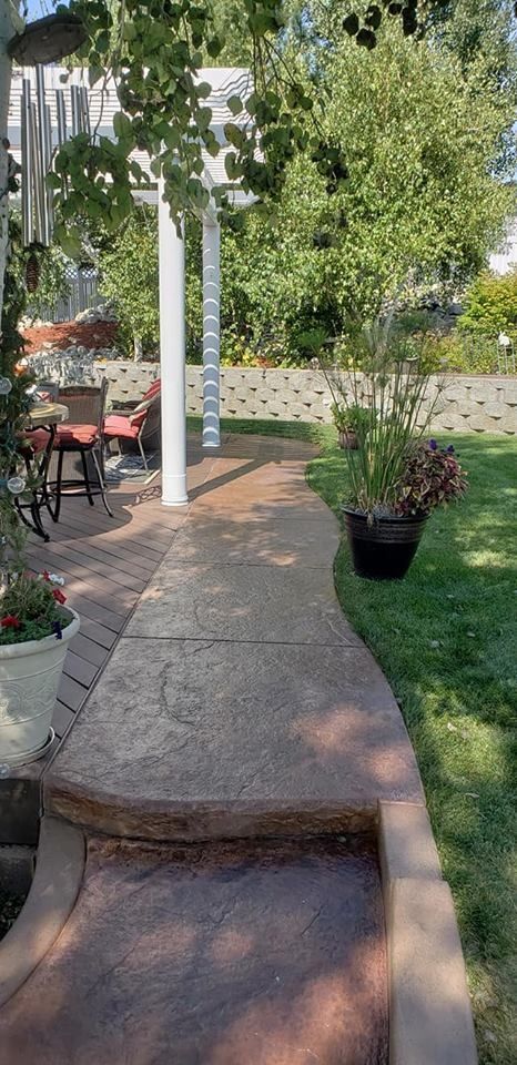 A walkway leading to a patio with a table and chairs.