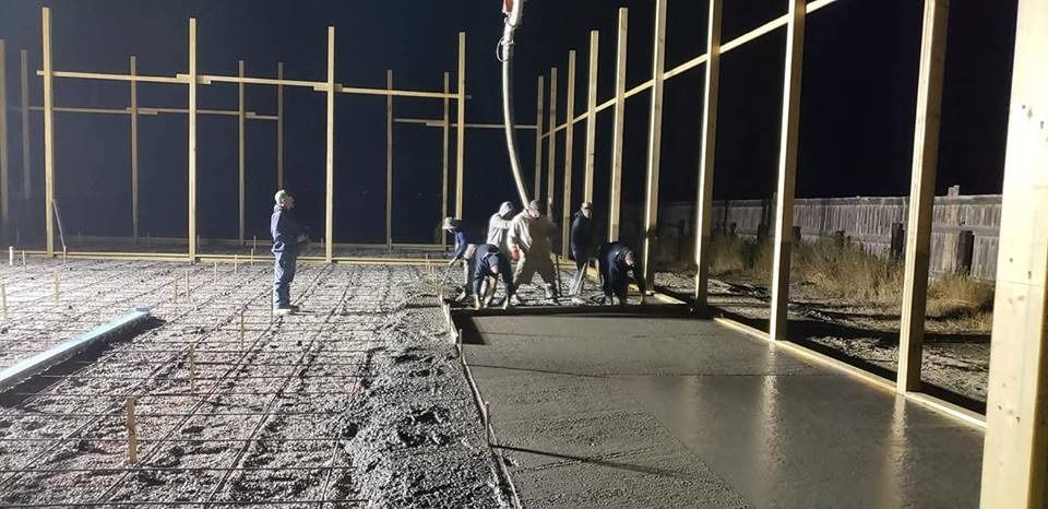 A group of people are working on a concrete floor at night.