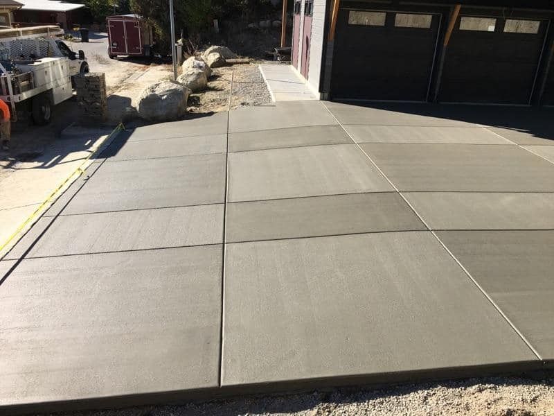 A concrete driveway is being built in front of a garage.