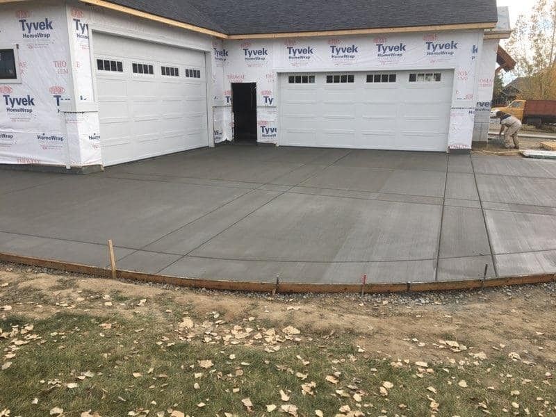 A concrete driveway is being built in front of a garage.
