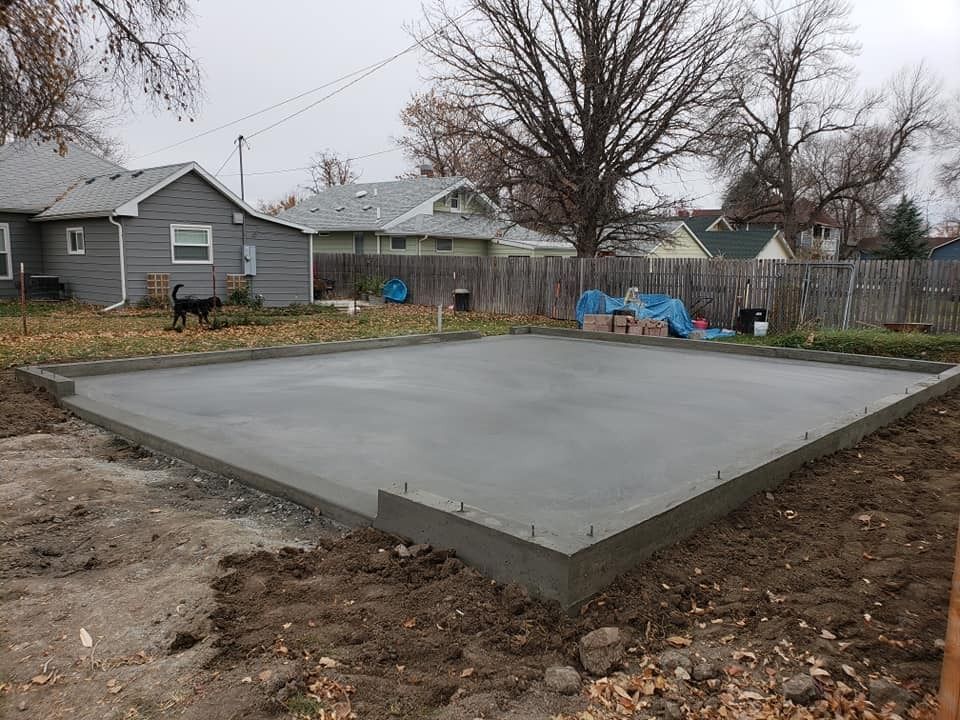 A concrete foundation is being built in the backyard of a house.
