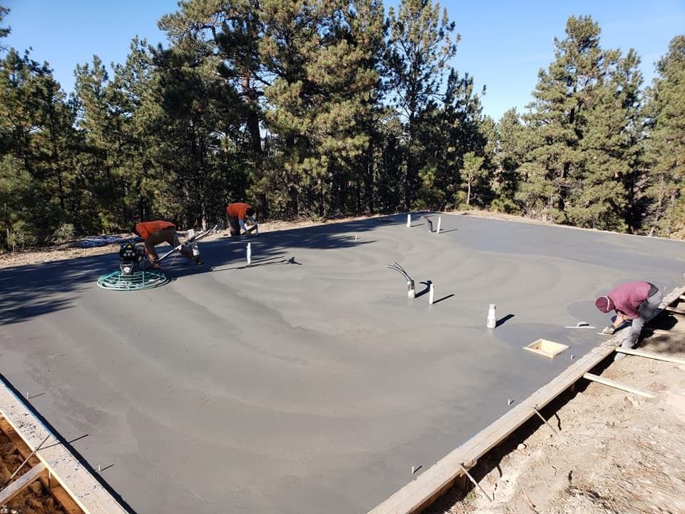 A man is working on a concrete floor with trees in the background