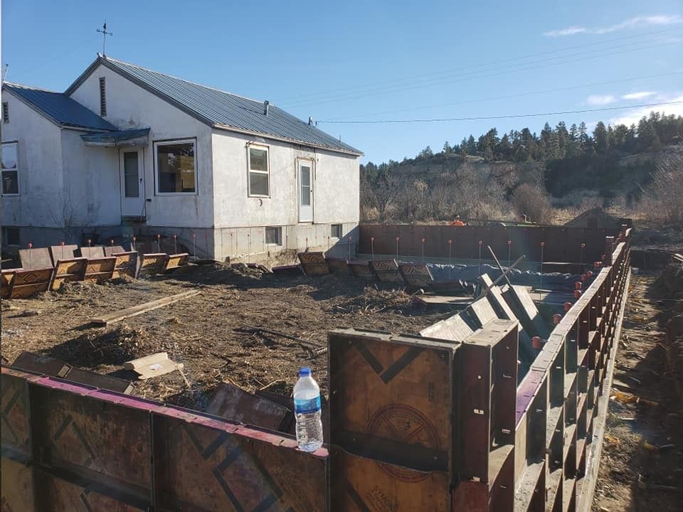 A bottle of water is sitting on a wooden fence in front of a house under construction.