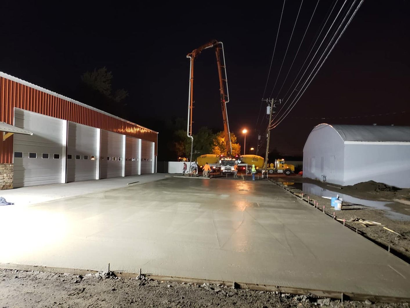 A concrete driveway is being poured in front of a building at night.