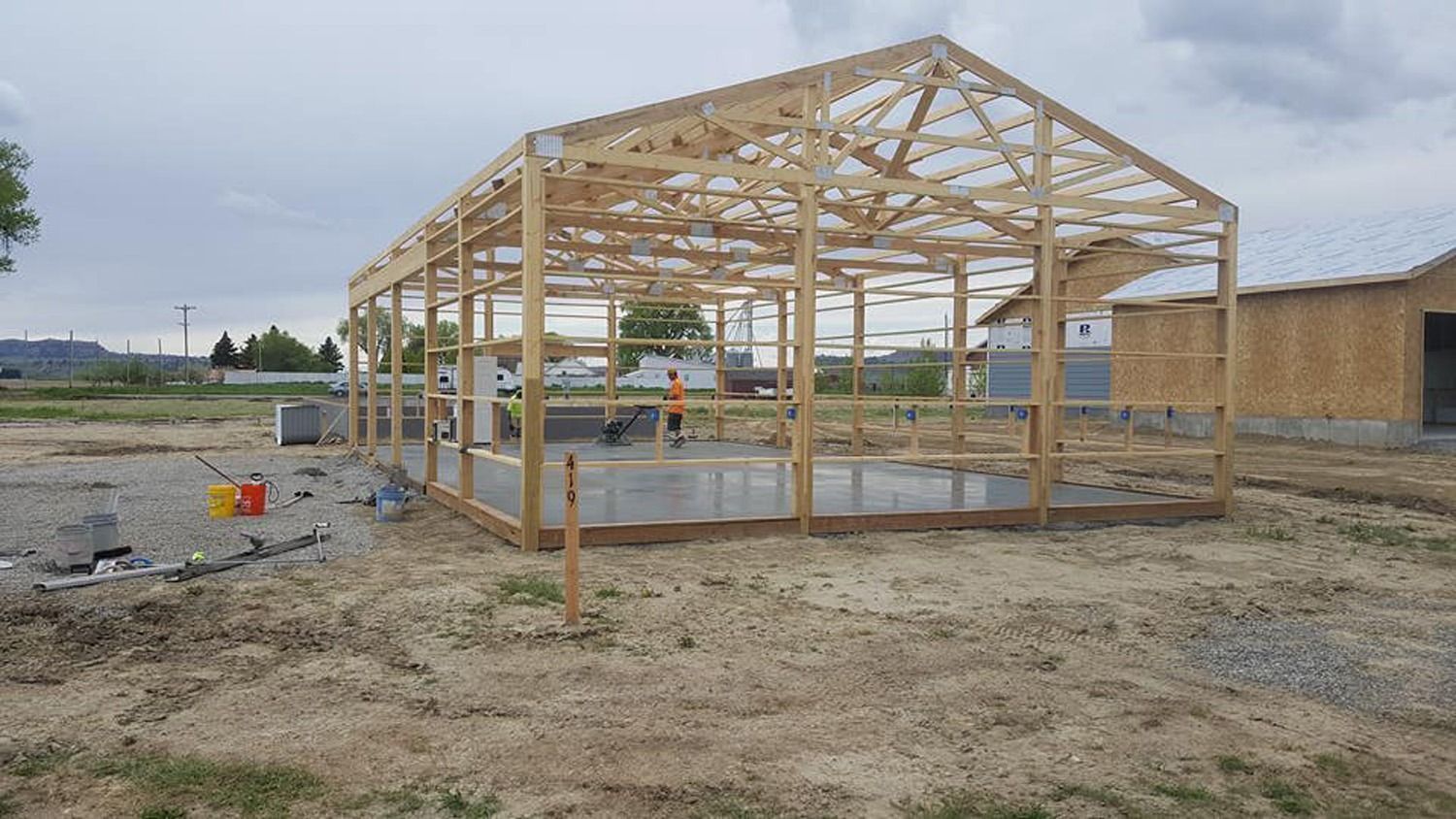 A large wooden structure is being built in a dirt field.