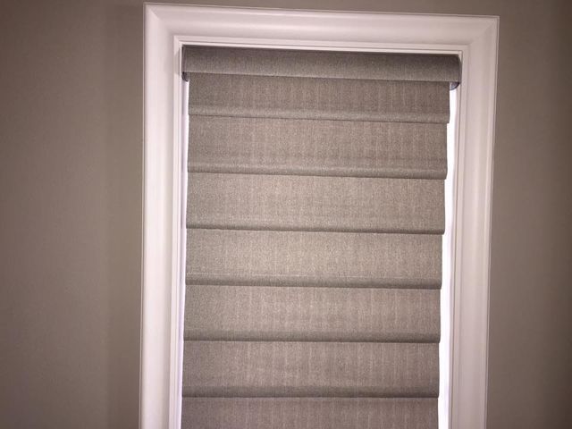 A Window With A Gray Roman Shade On It – Lubbock, TX – Wilson Blind & Shutter