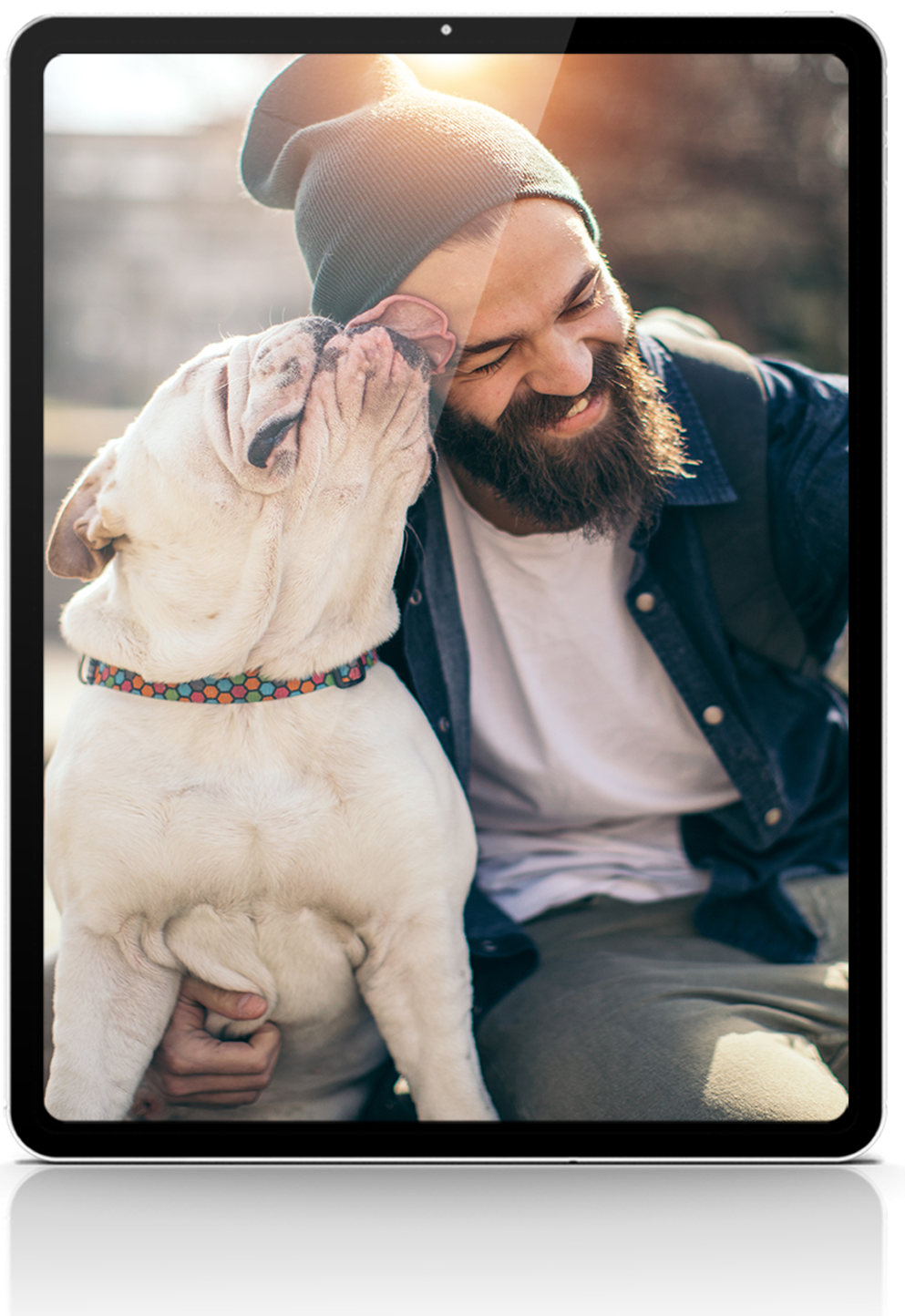 A man with a beard is sitting next to a white dog on a tablet.