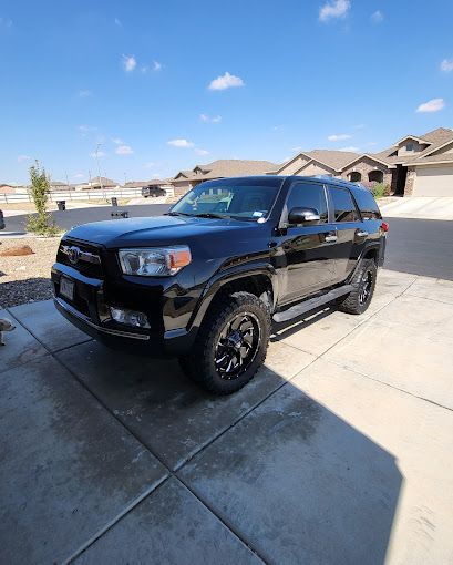 A black suv is parked in a driveway in front of a house.