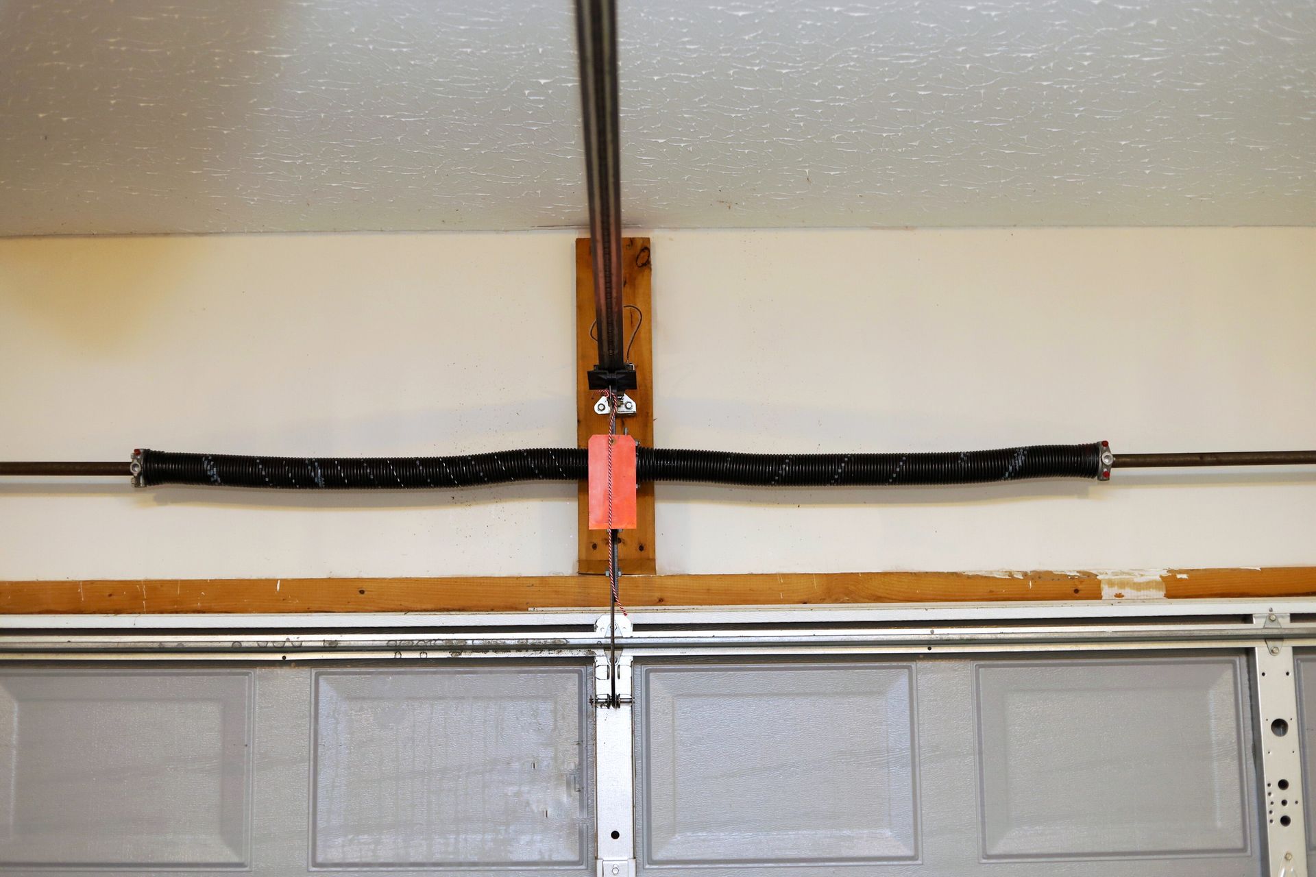Garage door torsion spring system above the door, with springs stretched horizontally.