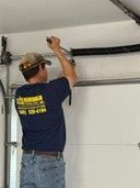 A man is working on a garage door track repair.