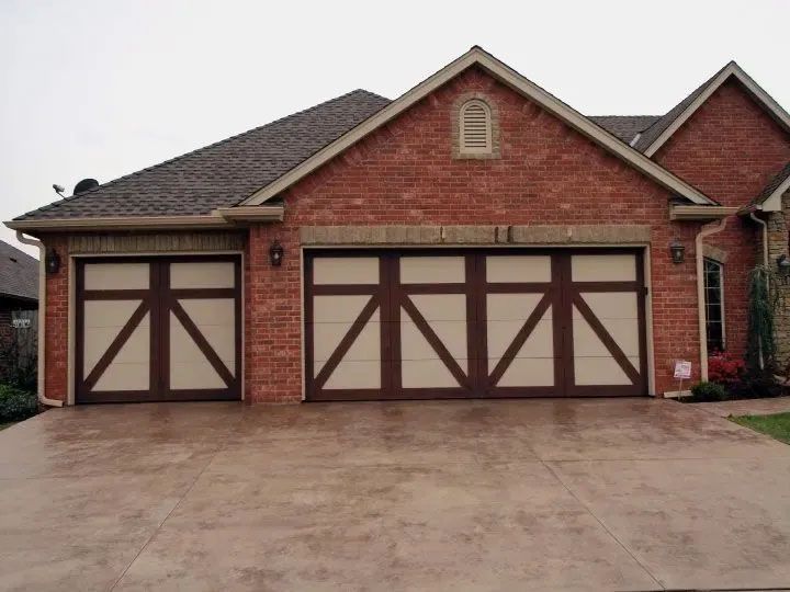 Two-car garage with brown and tan paneled doors, set against a brick house with a brown shingle roof.