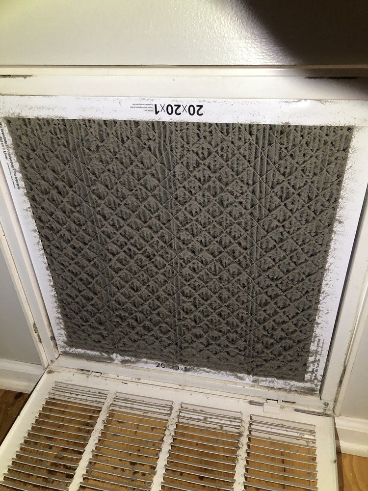 A close up of a dirty air filter on a wall.