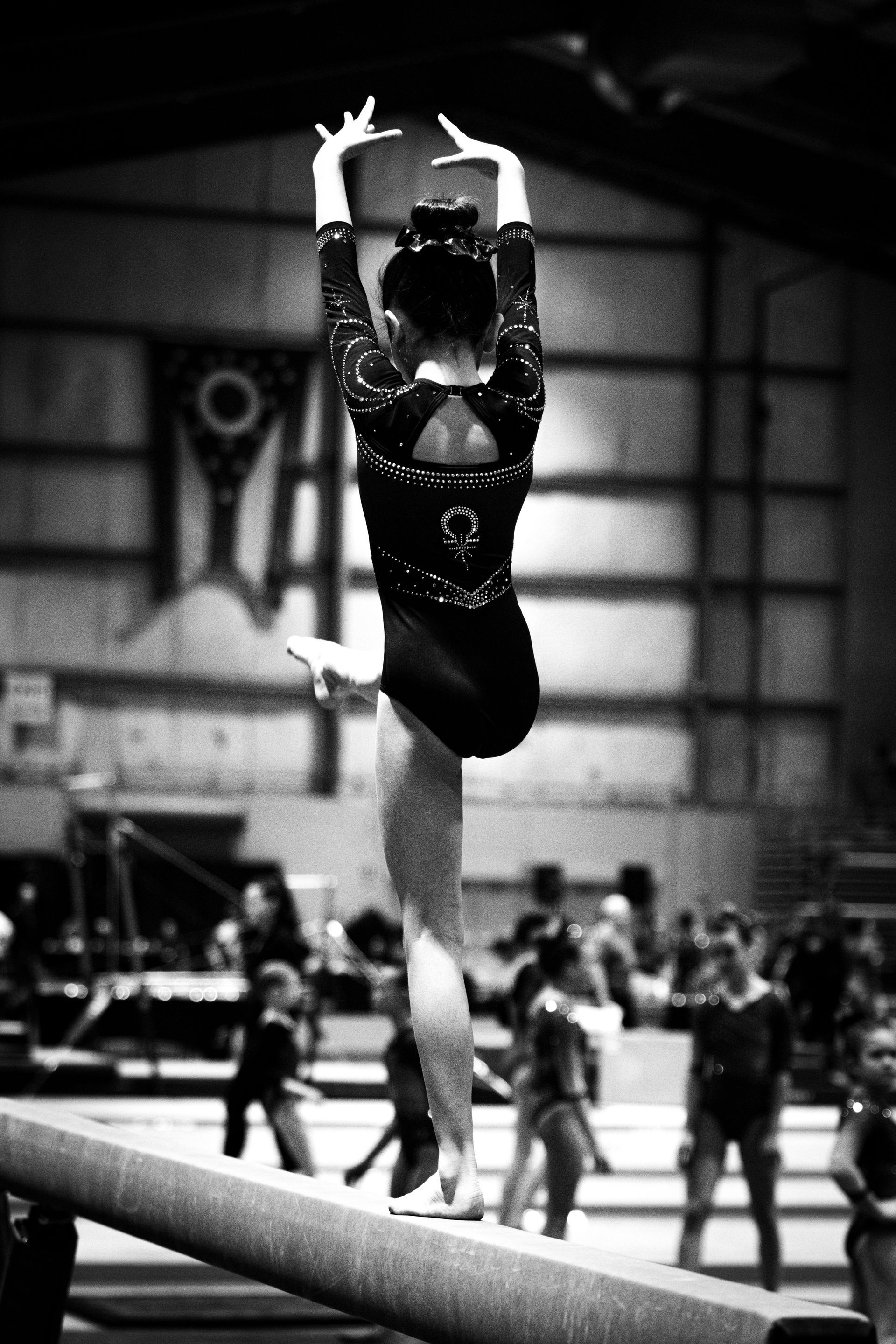 A black and white photo of a gymnast on a balance beam.