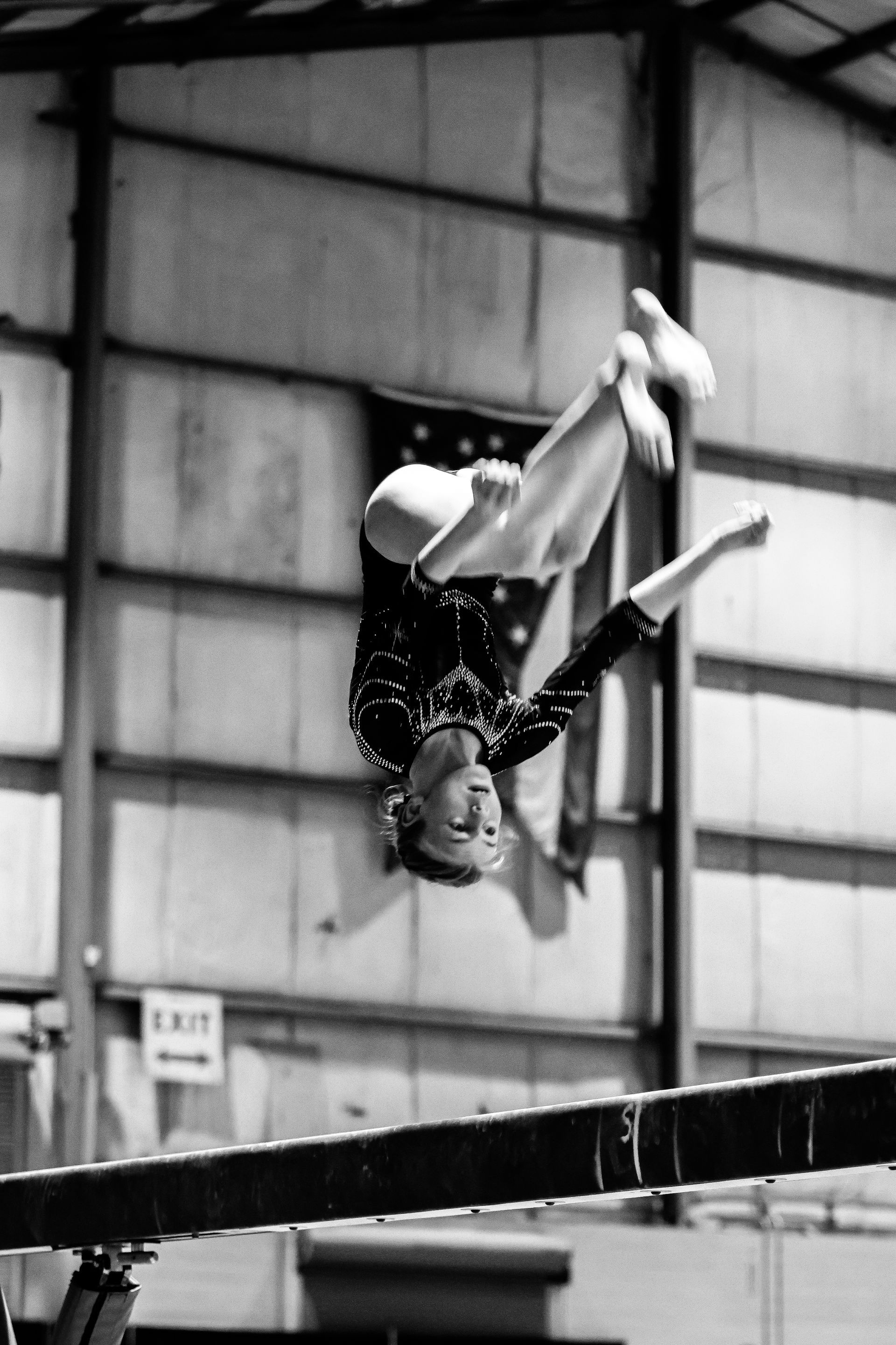 A black and white photo of a gymnast on a balance beam