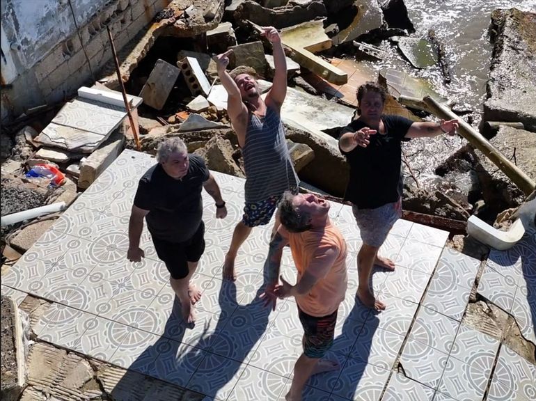 A group of men are standing on a tiled floor with their arms in the air.