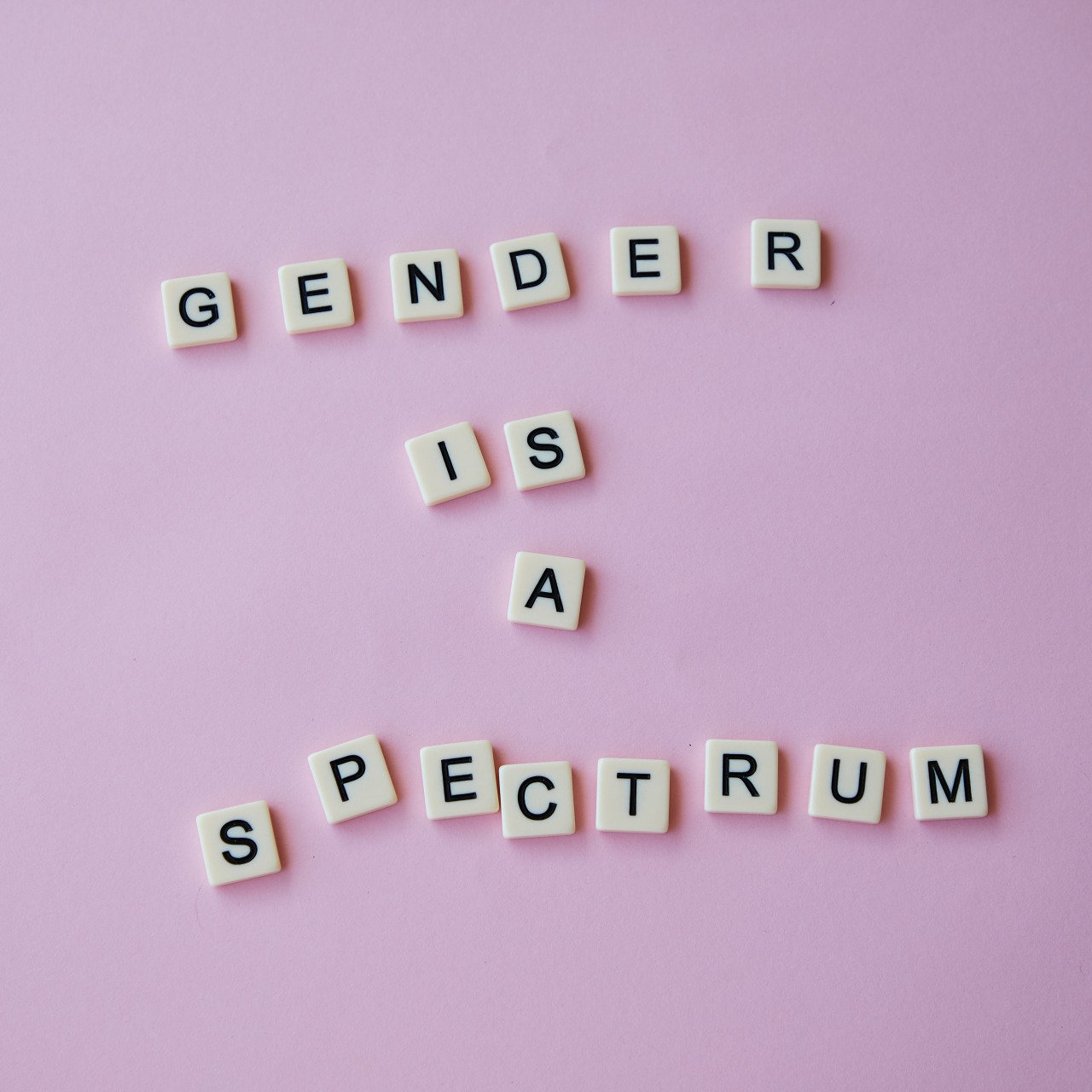 Het woord geslacht is geschreven in scrabble-letters op een roze achtergrond.