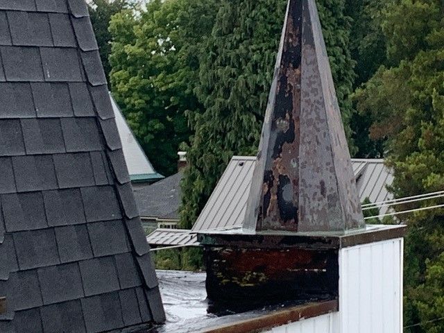 A man on a ladder is painting the side of a house