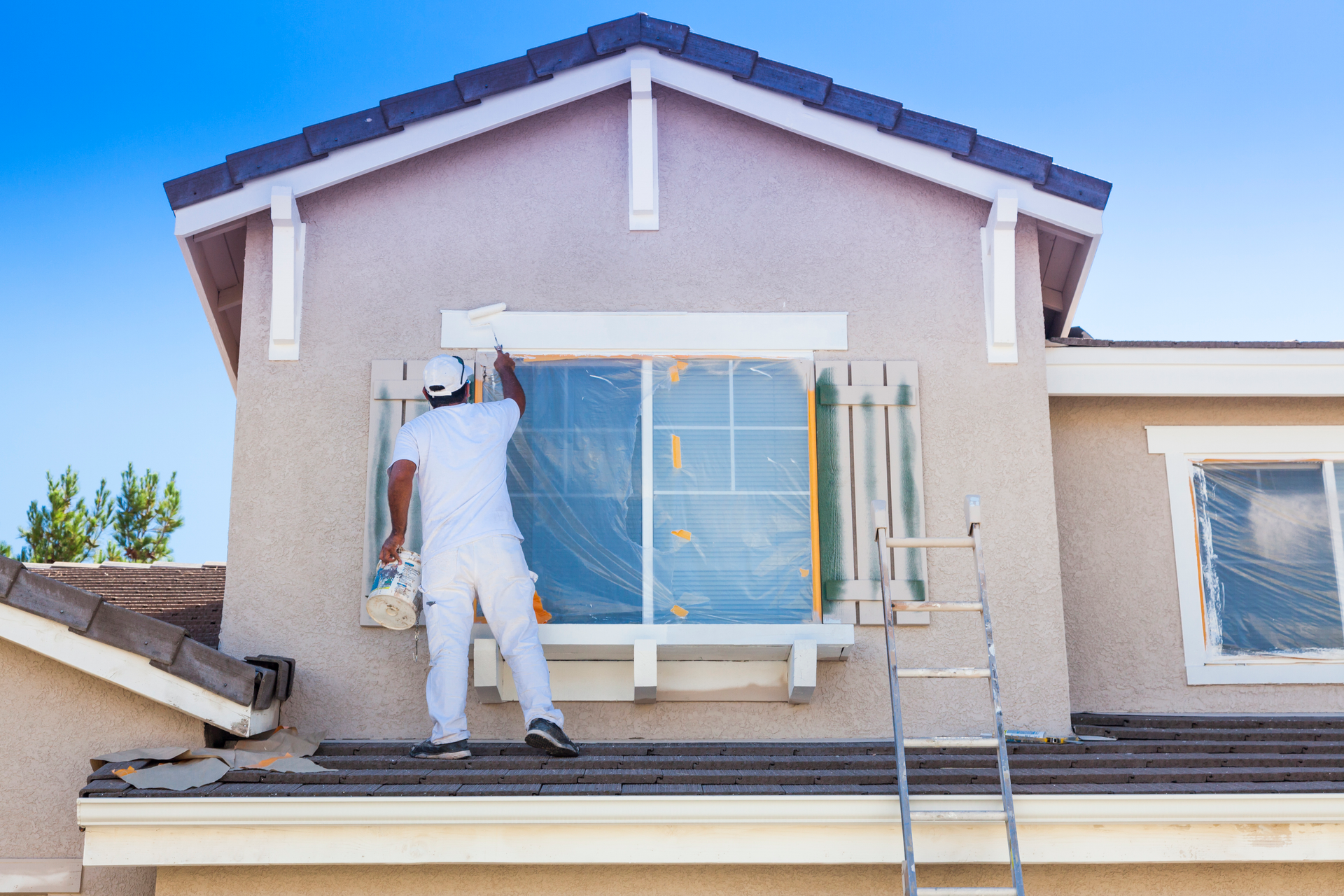 A paint roller is being used to paint the side of a house