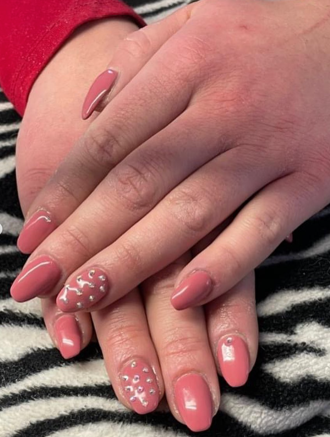 Un primo piano delle unghie di una persona su una coperta con stampa zebrata.