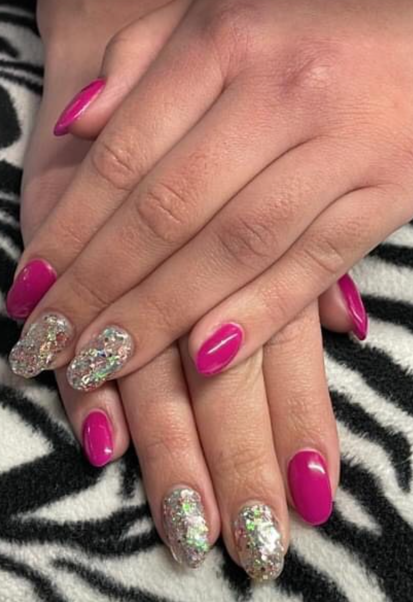 Un primo piano delle mani di una donna con unghie rosa e argento su una coperta con stampa zebrata.