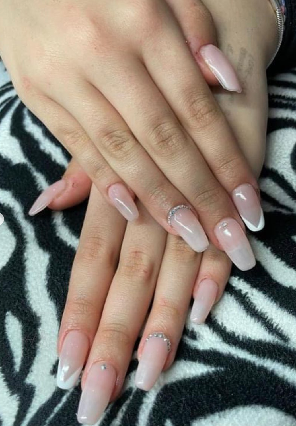 Un primo piano delle unghie di una donna su una coperta con stampa zebrata.