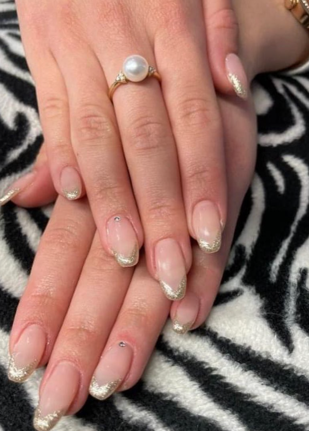 Un primo piano delle unghie di una donna con un anello al dito.