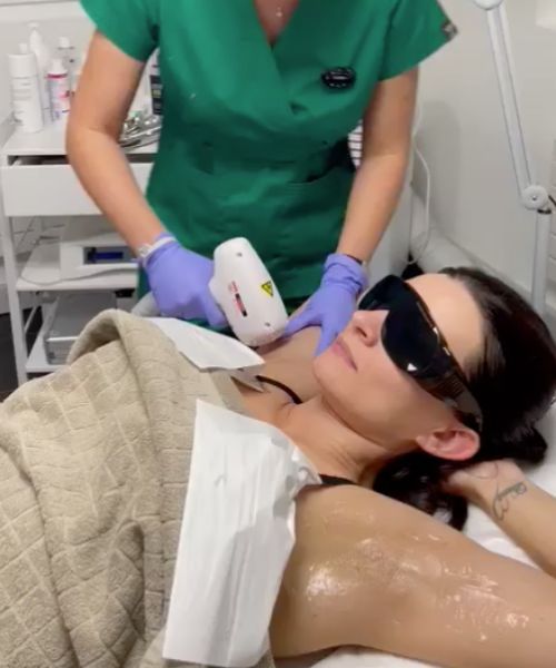 Una donna che indossa occhiali da sole sta ricevendo un trattamento di depilazione