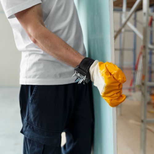 A man wearing yellow gloves is leaning against a wall